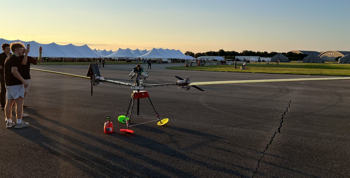Stella 2 on the tarmac at sunset, with the team standing beside it